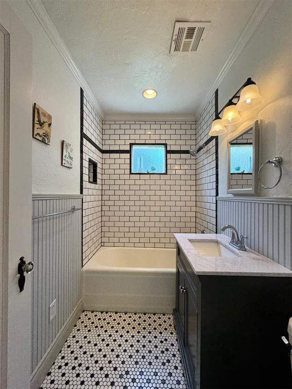 2252 NW 37th St, Oklahoma City, OK 73112 - bathroom with vanity, crown molding, a textured ceiling, wainscoting, and shower / bath combination