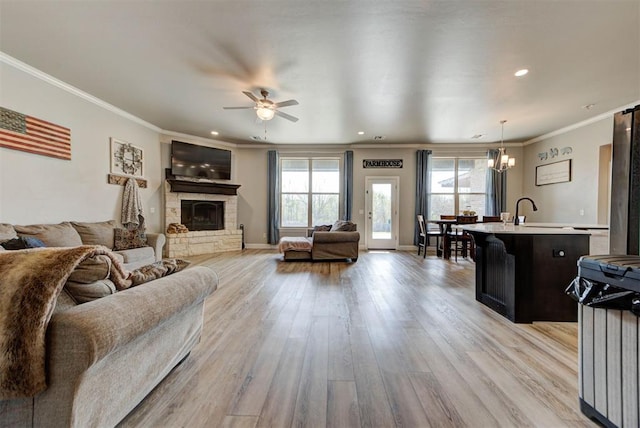 31352 Landrun Ave, Norman, OK 73072 - living area featuring ceiling fan, light wood-style floors, ornamental molding, a stone fireplace, and a chandelier