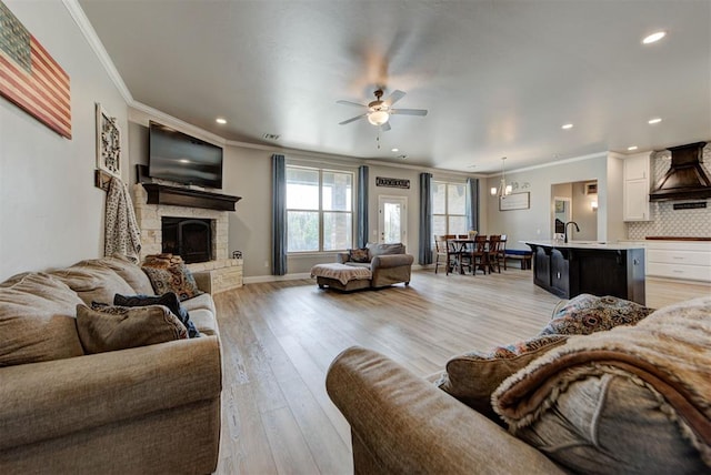 31352 Landrun Ave, Norman, OK 73072 - living area featuring ornamental molding, ceiling fan, light wood-style flooring, a stone fireplace, and recessed lighting