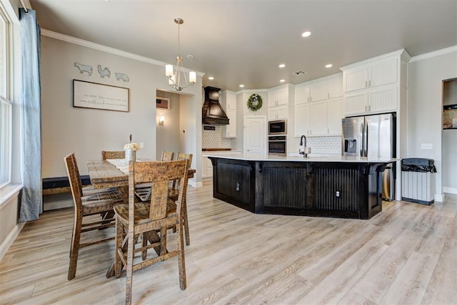 31352 Landrun Ave, Norman, OK 73072 - kitchen with appliances with stainless steel finishes, custom exhaust hood, light countertops, white cabinets, and tasteful backsplash