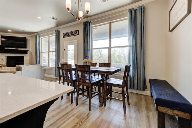 31352 Landrun Ave, Norman, OK 73072 - dining area with a chandelier, light wood-type flooring, ornamental molding, baseboards, and a stone fireplace