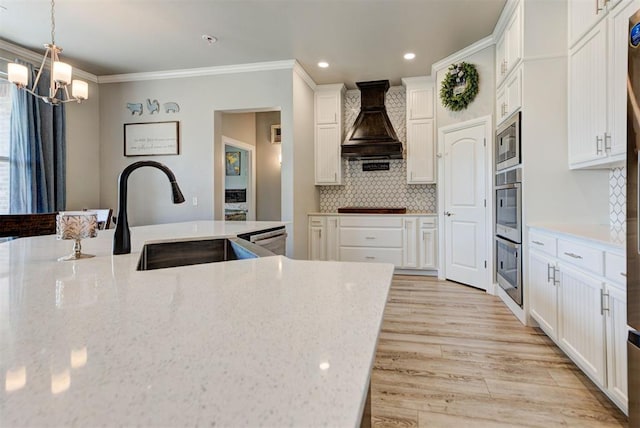 31352 Landrun Ave, Norman, OK 73072 - kitchen featuring custom range hood, a sink, a chandelier, tasteful backsplash, and white cabinetry