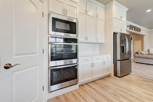 31352 Landrun Ave, Norman, OK 73072 - kitchen featuring appliances with stainless steel finishes, light wood-type flooring, backsplash, white cabinetry, and light countertops