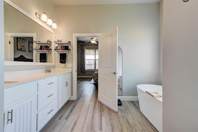 31352 Landrun Ave, Norman, OK 73072 - bathroom with a freestanding tub, double vanity, wood finished floors, a ceiling fan, and connected bathroom