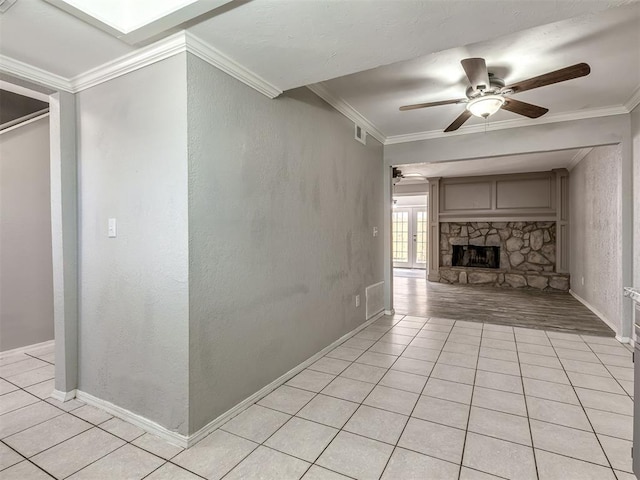 8131 NW 23rd St, Oklahoma City, OK 73127 - unfurnished living room featuring visible vents, baseboards, ornamental molding, a stone fireplace, and a ceiling fan