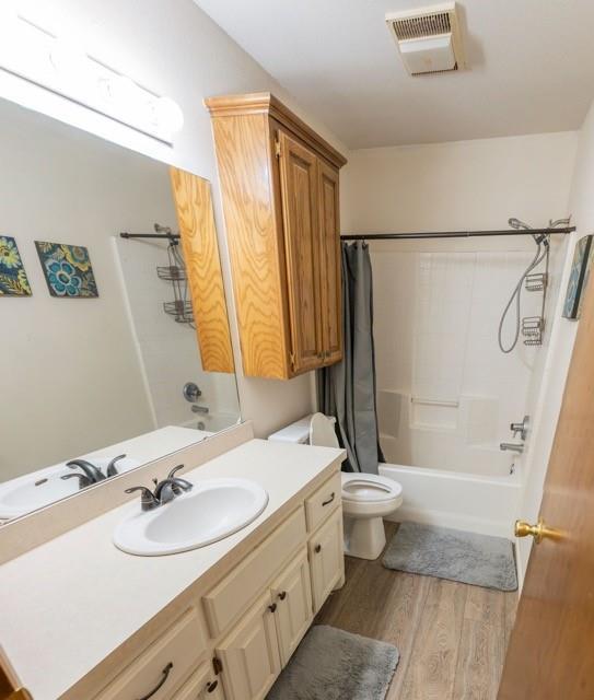 1189 N Blue Ridge Dr, Purcell, OK 73080 - bathroom with visible vents, shower / bath combination with curtain, toilet, vanity, and wood finished floors