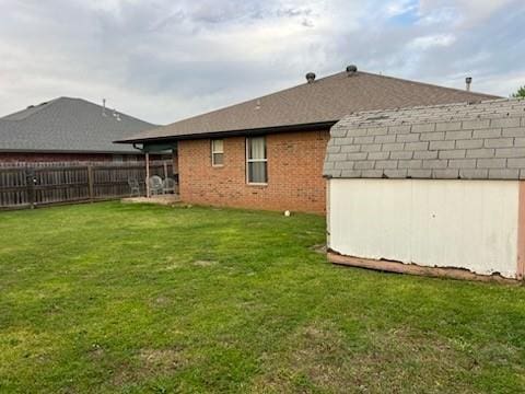 1189 N Blue Ridge Dr, Purcell, OK 73080 - back of house with an outdoor structure, brick siding, fence, a lawn, and a storage unit