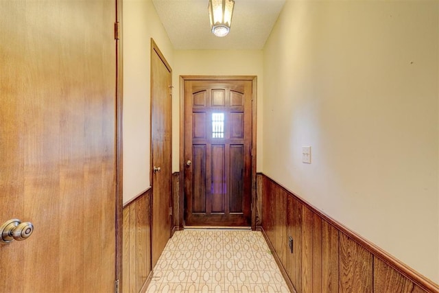 1809 W Aqua Clear Dr, Mustang, OK 73064 - doorway featuring a textured ceiling, wood walls, and a wainscoted wall