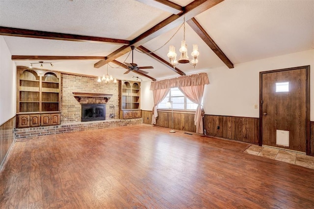 1809 W Aqua Clear Dr, Mustang, OK 73064 - unfurnished living room with a textured ceiling, vaulted ceiling with beams, a wainscoted wall, and wood finished floors