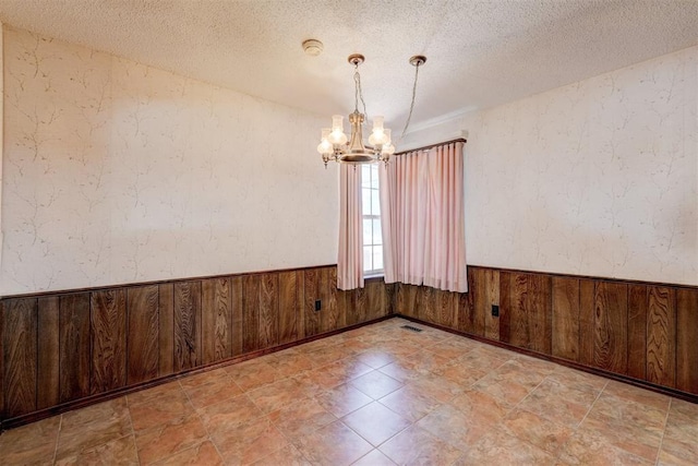 1809 W Aqua Clear Dr, Mustang, OK 73064 - spare room featuring an inviting chandelier, wainscoting, and a textured ceiling