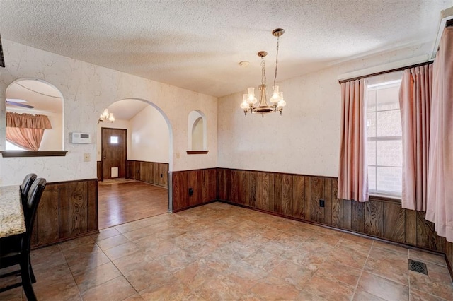 1809 W Aqua Clear Dr, Mustang, OK 73064 - unfurnished dining area with an inviting chandelier, wainscoting, and a textured ceiling