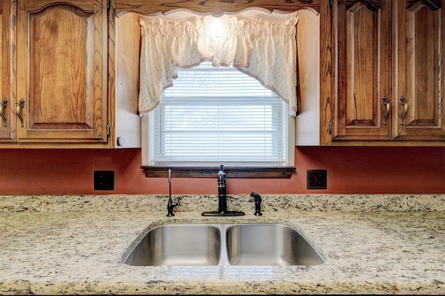 1809 W Aqua Clear Dr, Mustang, OK 73064 - kitchen with brown cabinetry, a sink, and light stone countertops