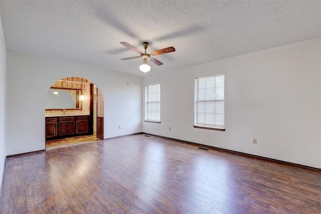 1809 W Aqua Clear Dr, Mustang, OK 73064 - unfurnished living room featuring arched walkways, a textured ceiling, a ceiling fan, visible vents, and wood finished floors