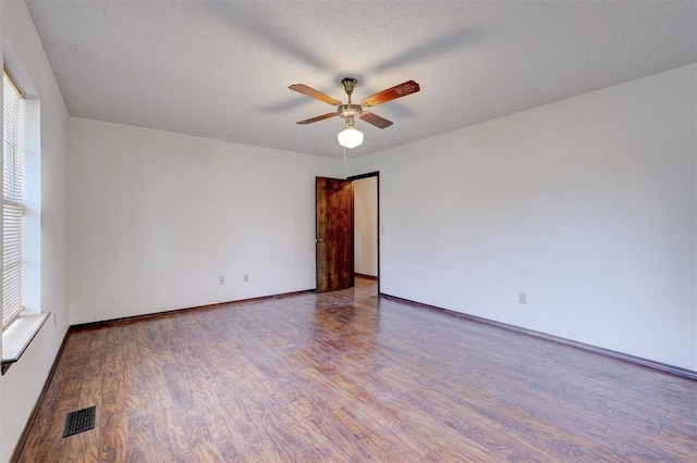 1809 W Aqua Clear Dr, Mustang, OK 73064 - spare room with visible vents, a textured ceiling, a ceiling fan, and wood finished floors