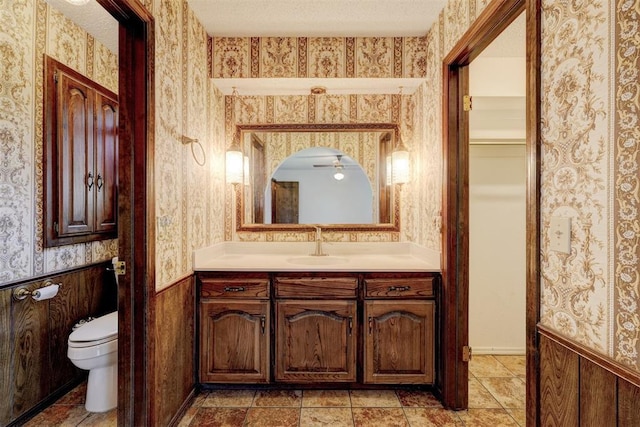 1809 W Aqua Clear Dr, Mustang, OK 73064 - bathroom featuring toilet, a wainscoted wall, a textured ceiling, and wallpapered walls