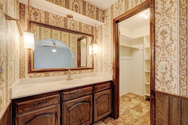1809 W Aqua Clear Dr, Mustang, OK 73064 - bathroom with wallpapered walls, vanity, a ceiling fan, and a walk in closet
