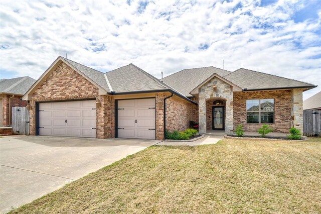 french country style house with driveway, brick siding, a front yard, and a garage