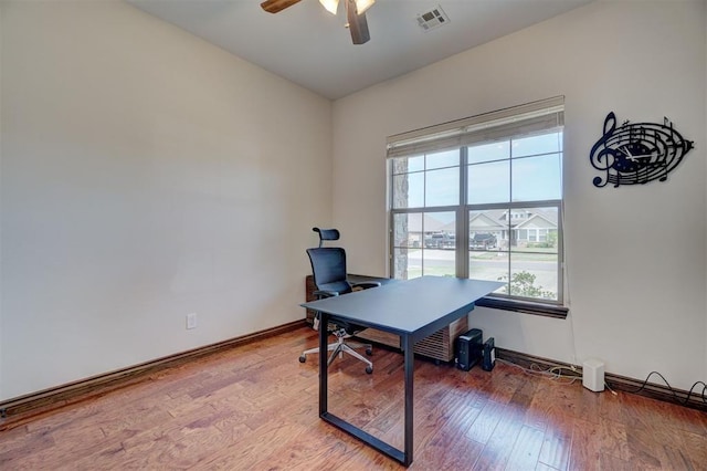 office area with light wood-style flooring, visible vents, a ceiling fan, and baseboards