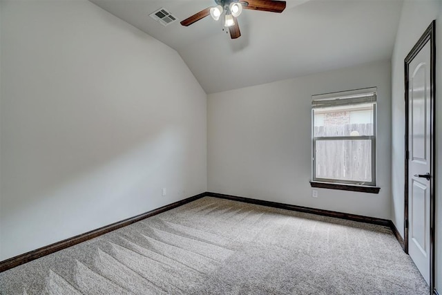 carpeted empty room with vaulted ceiling, visible vents, a ceiling fan, and baseboards