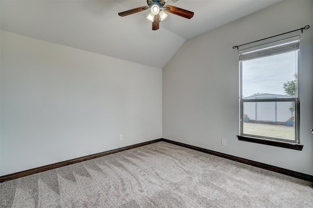 carpeted empty room with vaulted ceiling, baseboards, and a ceiling fan
