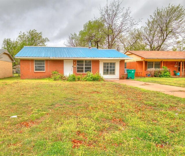 416 NW 81st St, Oklahoma City, OK 73114 - ranch-style home with metal roof, a front lawn, and brick siding