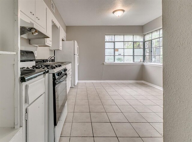 416 NW 81st St, Oklahoma City, OK 73114 - kitchen with light tile patterned floors, black range with gas stovetop, a textured ceiling, white cabinetry, and baseboards