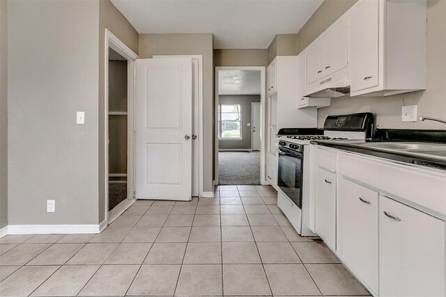 416 NW 81st St, Oklahoma City, OK 73114 - kitchen with baseboards, light tile patterned floors, white cabinets, gas range, and under cabinet range hood