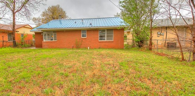 416 NW 81st St, Oklahoma City, OK 73114 - rear view of house featuring metal roof, fence, and a lawn