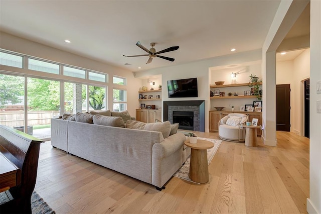 living area with recessed lighting, light wood-style floors, ceiling fan, a fireplace, and baseboards