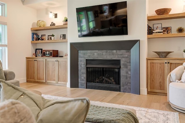 living area featuring light wood finished floors and a brick fireplace