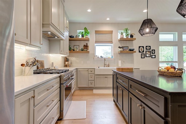 kitchen featuring recessed lighting, a sink, open shelves, tasteful backsplash, and stainless steel stove