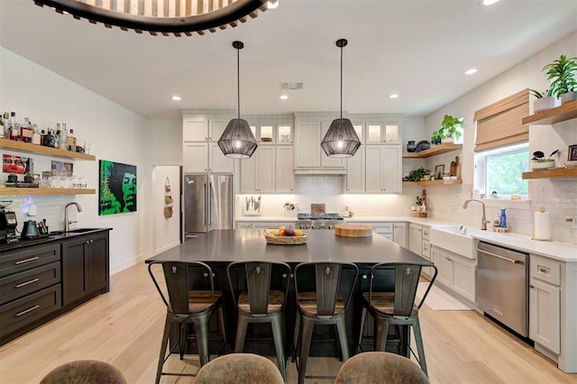 kitchen with tasteful backsplash, a kitchen breakfast bar, open shelves, and appliances with stainless steel finishes