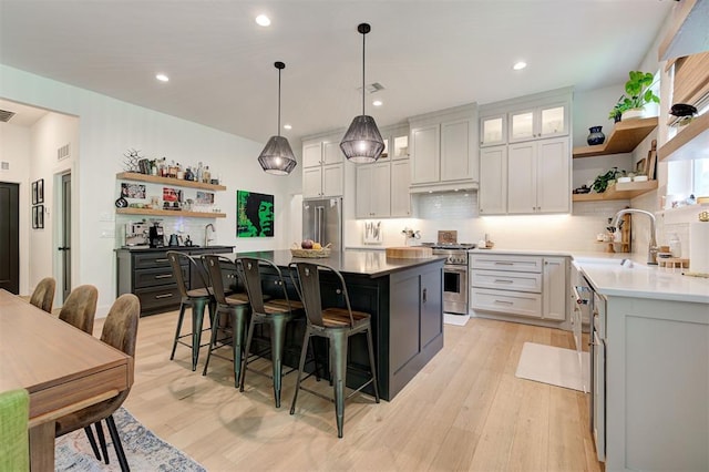 kitchen with open shelves, premium appliances, a kitchen bar, and a sink