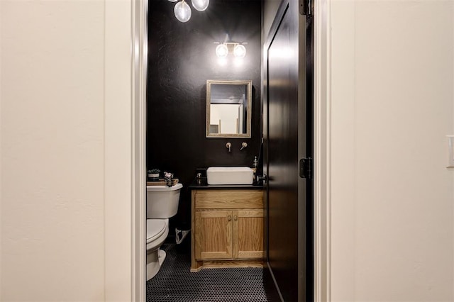 half bath with tile patterned floors, toilet, and vanity