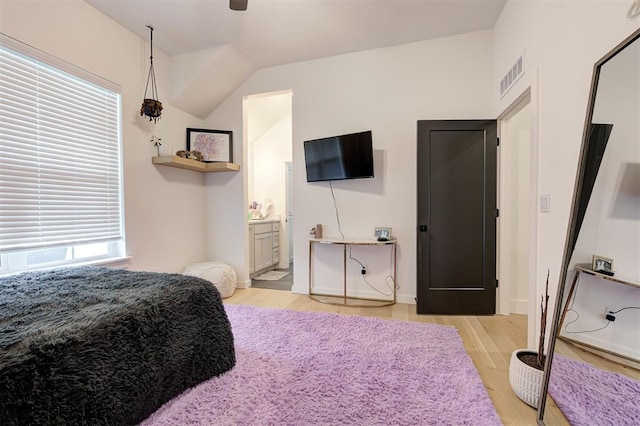 bedroom with visible vents, wood finished floors, and ensuite bath