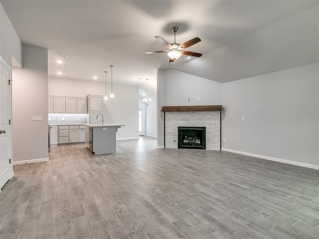 1680 Addington Rd, Newcastle, OK 73065 - unfurnished living room featuring baseboards, a stone fireplace, a ceiling fan, light wood finished floors, and lofted ceiling