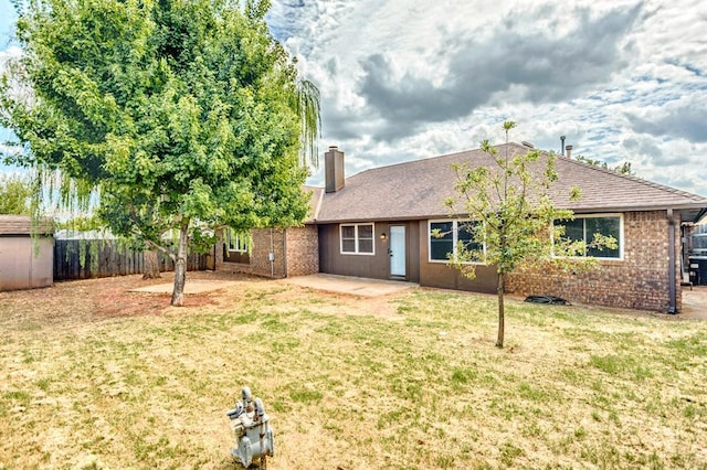 1021 NW 167th St, Edmond, OK 73012 - rear view of house with a yard, a chimney, a fenced backyard, an outdoor structure, and a patio