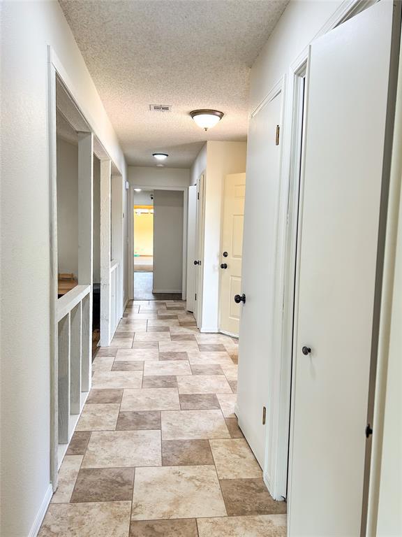 1016 Canyon Ridge Rd, Clinton, OK 73601 - hall featuring visible vents, a textured ceiling, and stone finish floor
