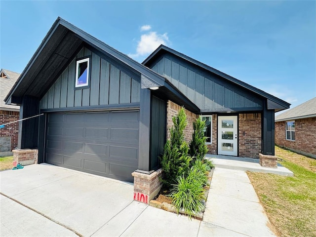 1101 SW 139th St, Oklahoma City, OK 73170 - view of front of home featuring a garage, board and batten siding, driveway, and brick siding