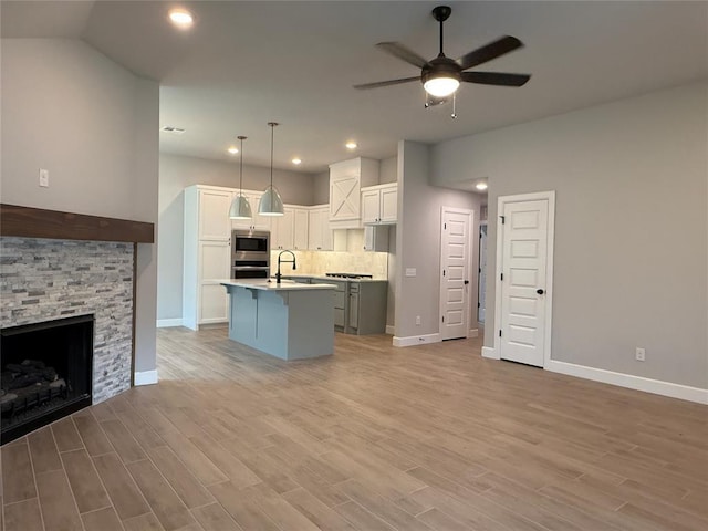 1220 SW 139th St, Oklahoma City, OK 73170 - kitchen with stainless steel appliances, open floor plan, ceiling fan, an island with sink, and light wood-style floors