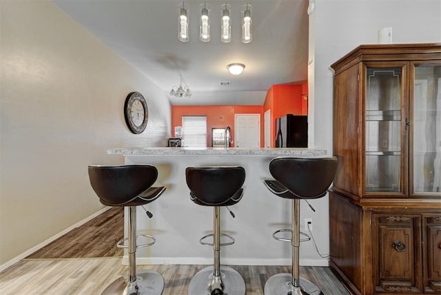 1641 Tumbleweed Way, El Reno, OK 73036 - kitchen with freestanding refrigerator, baseboards, a sink, a kitchen bar, and wood finished floors