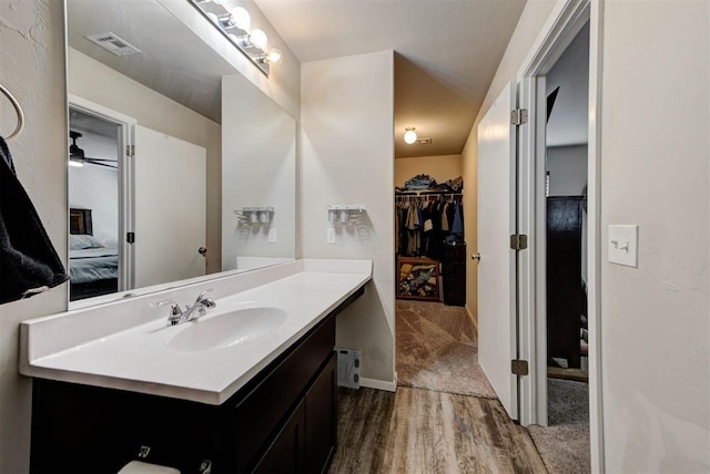 1641 Tumbleweed Way, El Reno, OK 73036 - bathroom with visible vents, connected bathroom, vanity, a walk in closet, and wood finished floors