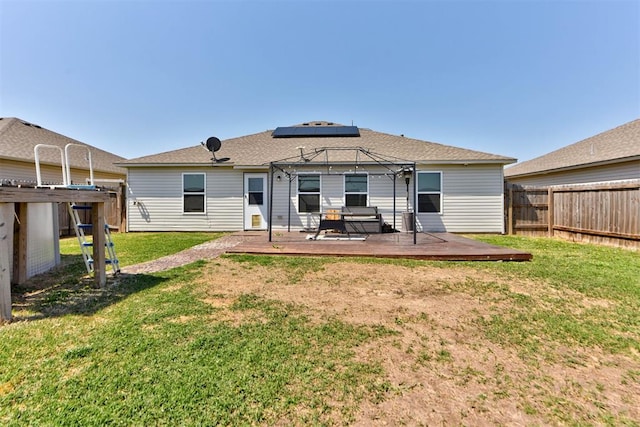 1641 Tumbleweed Way, El Reno, OK 73036 - back of property with a deck, a yard, a fenced backyard, roof mounted solar panels, and a pergola
