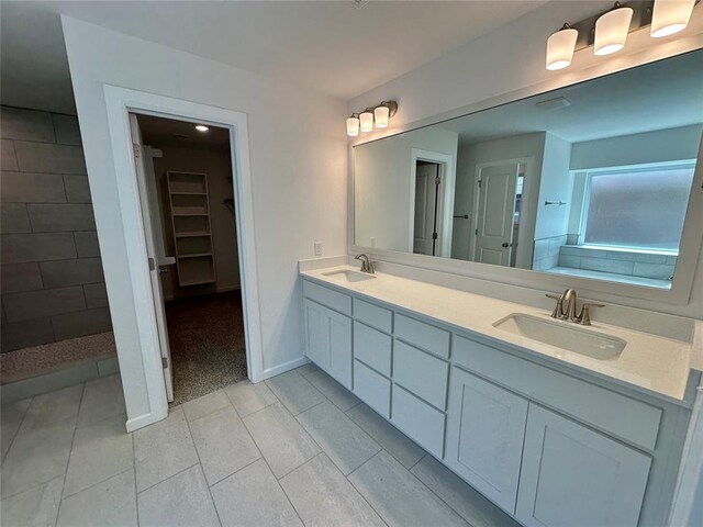 8605 NW 76th St, Oklahoma City, OK 73132 - bathroom featuring double vanity, tile patterned flooring, a walk in closet, a tile shower, and baseboards