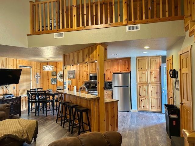 713 Whispering Water Dr, Fort Cobb, OK 73038 - kitchen featuring visible vents, a high ceiling, open floor plan, wood finished floors, and stainless steel appliances