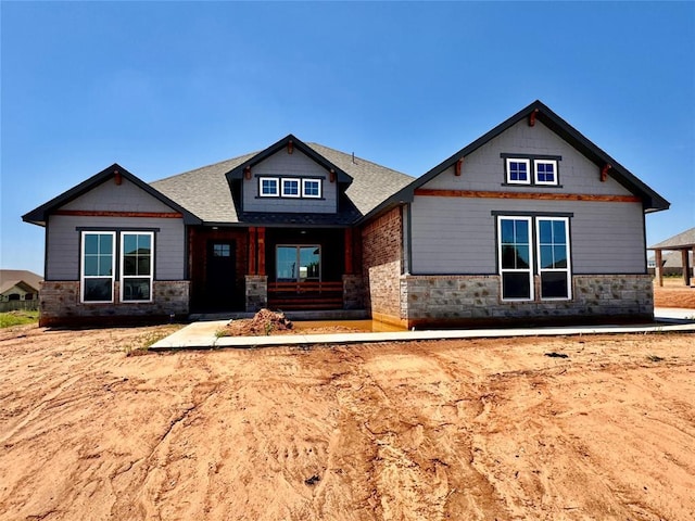 10116 NW 100th St, Yukon, OK 73099 - craftsman-style house featuring roof with shingles, stone siding, and covered porch