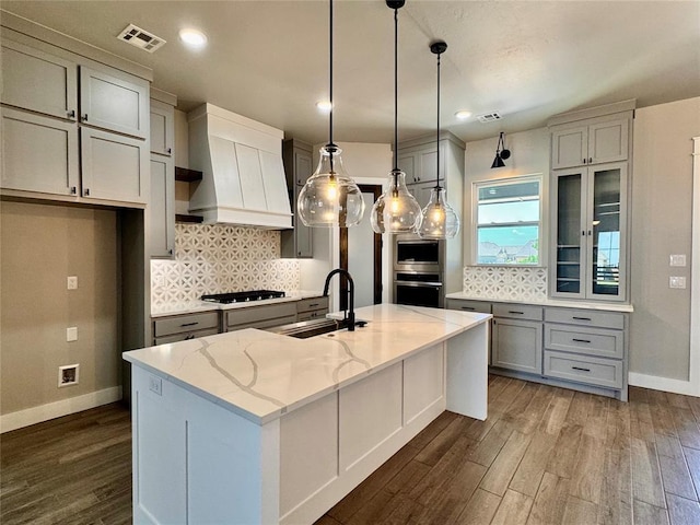 10116 NW 100th St, Yukon, OK 73099 - kitchen featuring custom exhaust hood, appliances with stainless steel finishes, dark wood-style floors, light stone countertops, and backsplash