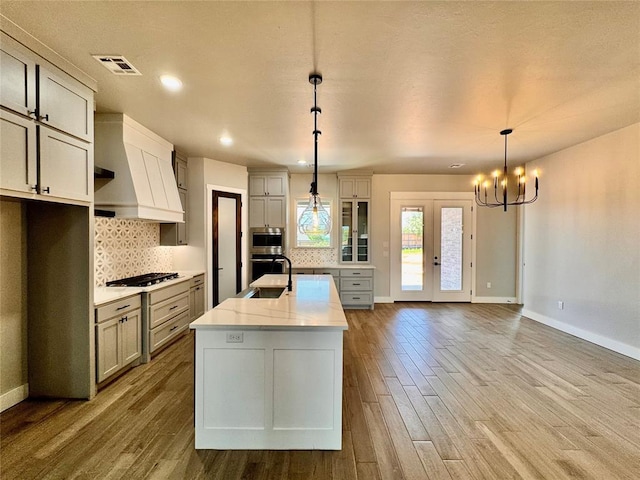 10116 NW 100th St, Yukon, OK 73099 - kitchen with stainless steel appliances, custom range hood, wood finished floors, decorative backsplash, and recessed lighting