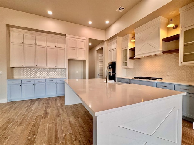 10132 NW 100th St, Yukon, OK 73099 - kitchen featuring light wood-style floors, a spacious island, tasteful backsplash, recessed lighting, and white cabinetry