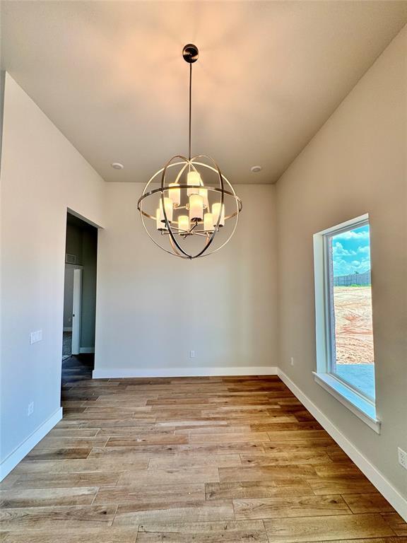 10132 NW 100th St, Yukon, OK 73099 - spare room with a chandelier and wood finished floors